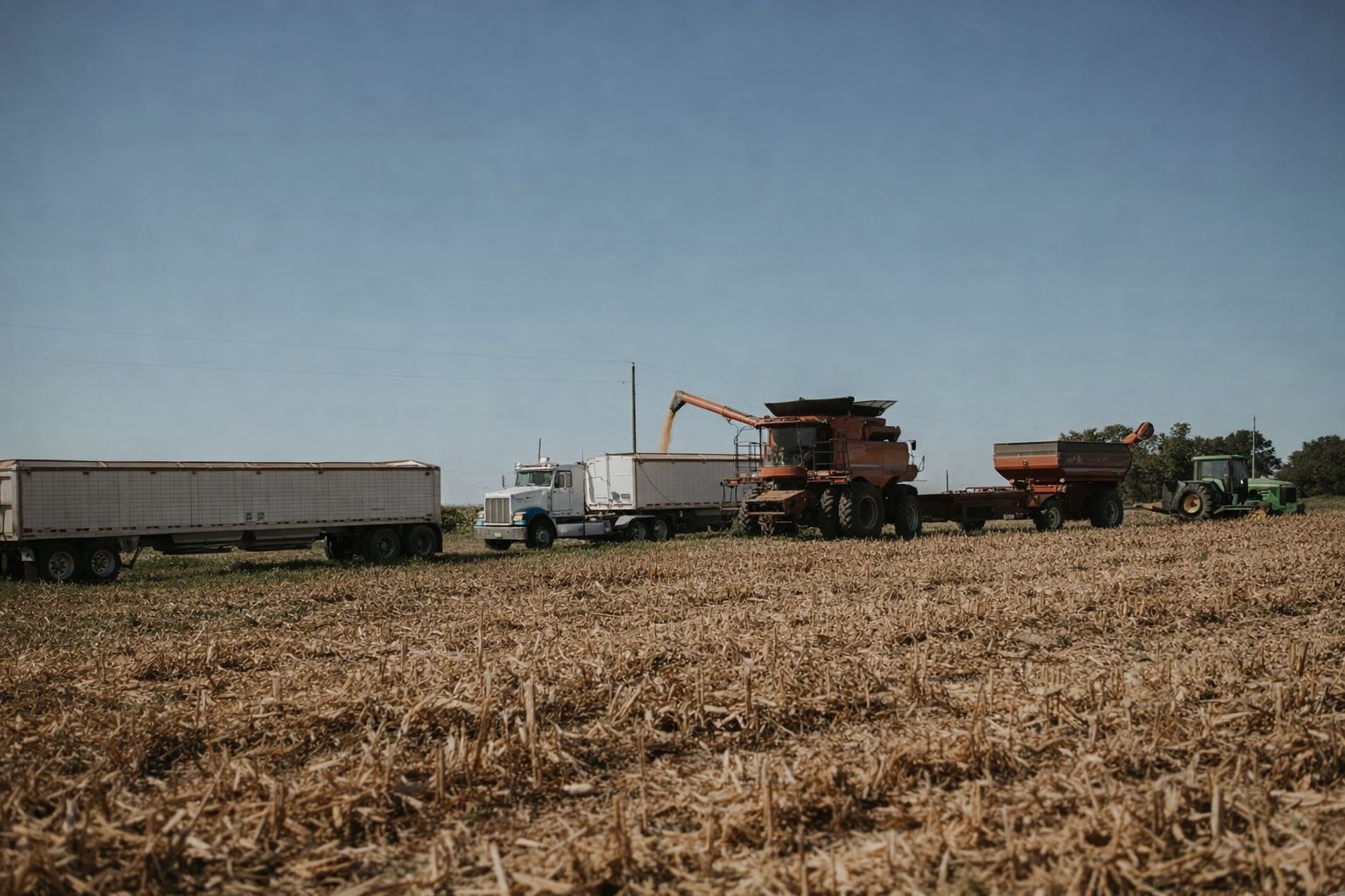 Skördetröska tömmer säd i en lastbil på en åker vid en familjegård.